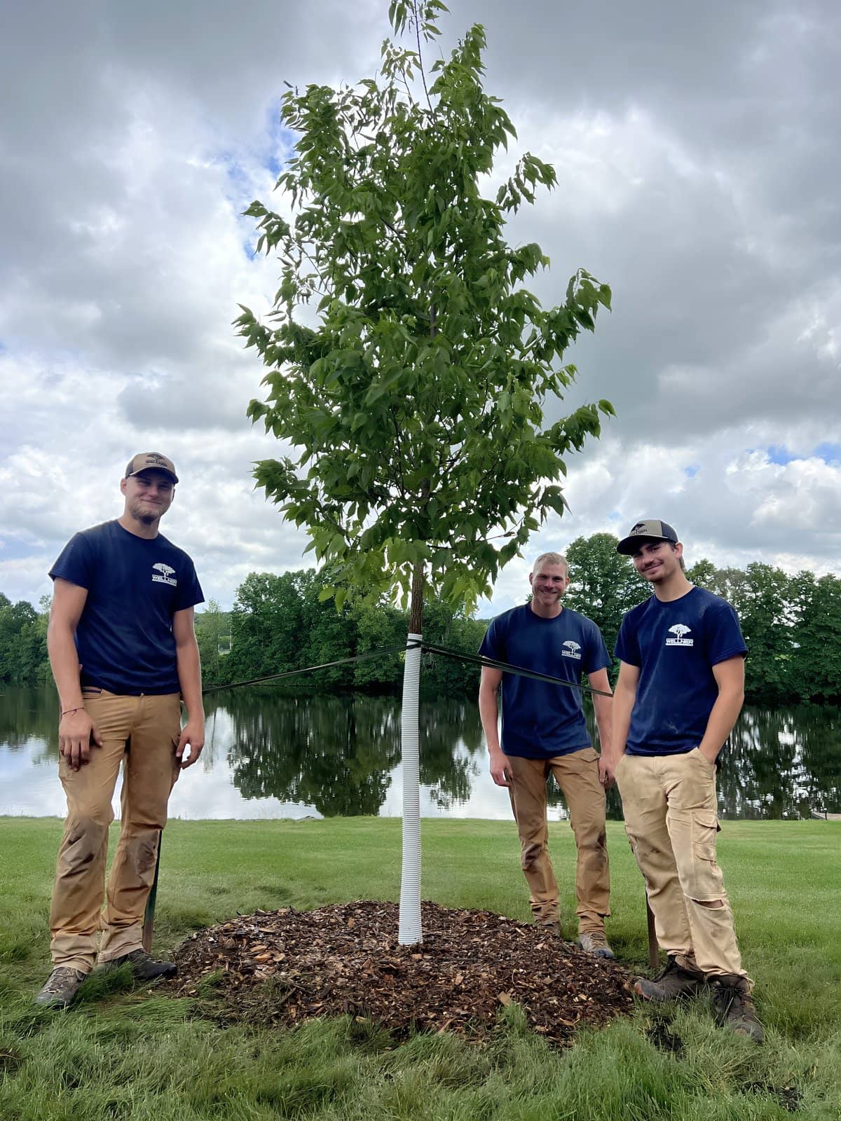 The Wellner Arboriculture crew with a newly planted tree beside the water